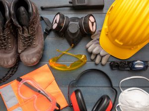 Work safety protection equipment. A hard hat, googles, a ventilation mask, headphones, work light, and work boots.