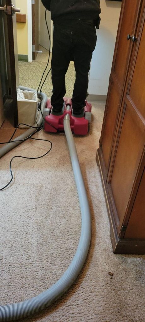 PuroClean technician using equipment to dry water from burst pipe.