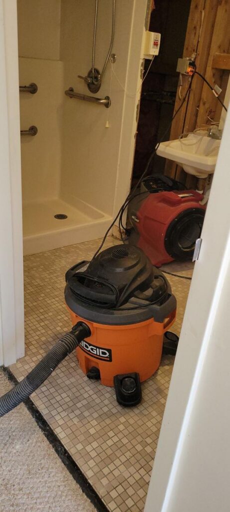 Equipment set up in bathroom to deal with water damage from burst pipe.