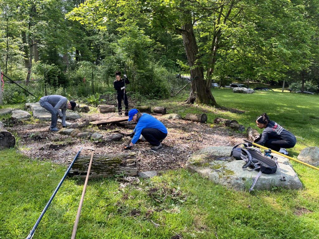 PuroClean volunteers weeding around the fire pit at Paradise Farm during a community cleanup