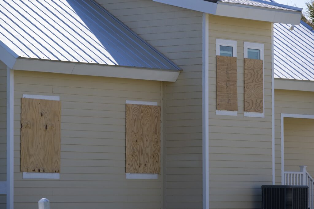 Boarded-up windows with plywood storm shutters