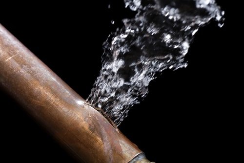 Burst copper water pipe spraying water — frozen pipe failure