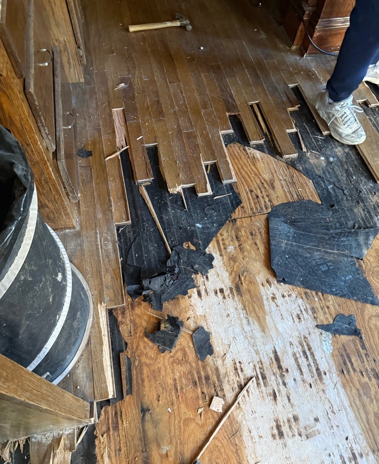 Water-damaged hardwood floor torn up mid-restoration during a PuroClean of East Cobb water damage job in Johns Creek