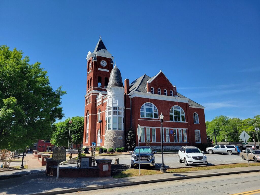 The Old Haralson County Courthouse in Buchanan, Georgia — the red-brick 1891 Queen Anne courthouse with its clock tower anchoring the county seat square