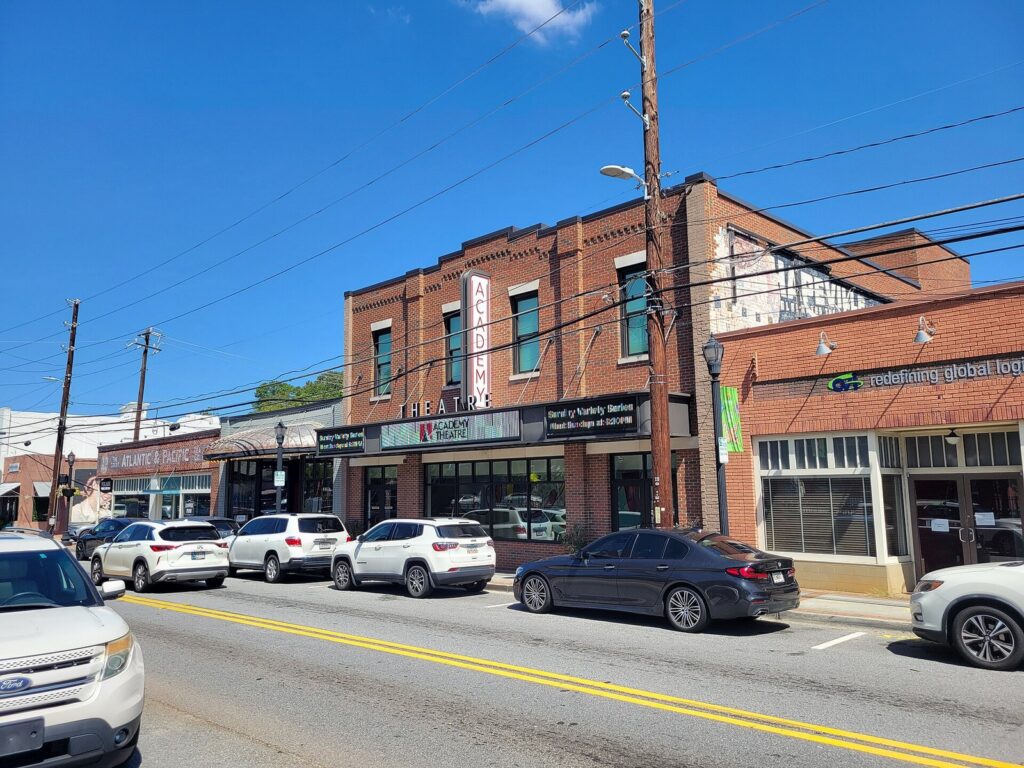 The historic Academy Theatre and brick storefronts on Central Avenue in downtown Hapeville, Georgia — the Main Street city chartered in 1891 beside the airport