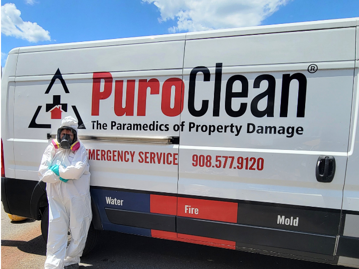puroclean biohazard services tech in PPE leaning against van