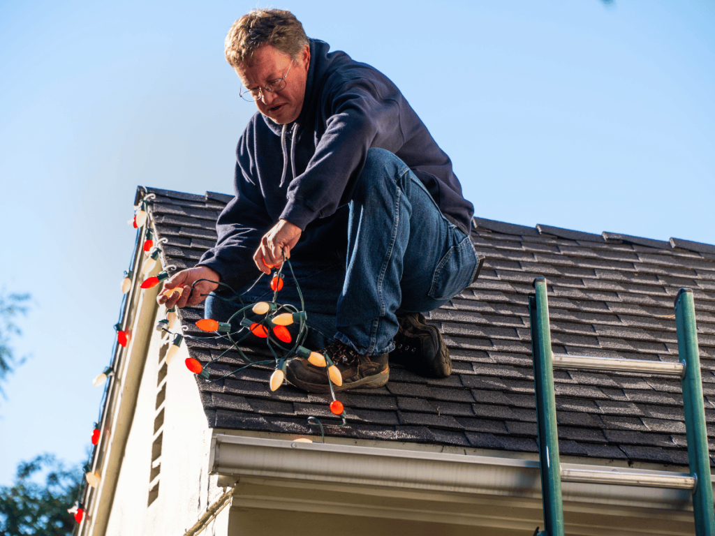 man on roof, strining Christmas lights