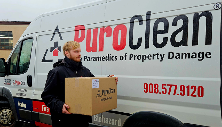 PuroClean team member carrying a box for content documentation and packout