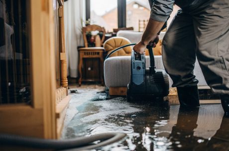 Technician extracting water from a flooded living room during water damage cleanup.