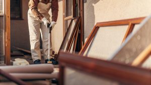 Professional hoarding cleanup worker safely removing items from cluttered home