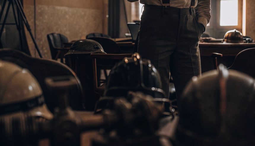 Vintage military helmets displayed on a table in a dimly lit historical room with a person standing in the background.