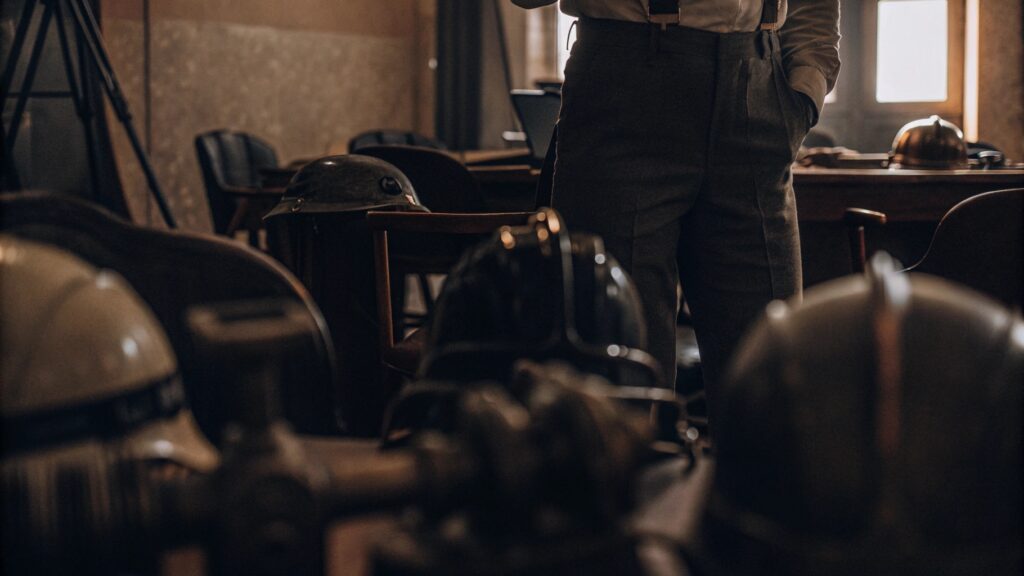 Vintage military helmets displayed on a table in a dimly lit historical room with a person standing in the background.