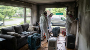 Three technicians in protective gear using industrial drying equipment during fire damage restoration in McLean, VA.