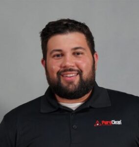 A smiling man with a beard wearing a black polo shirt with the PumpClean logo.