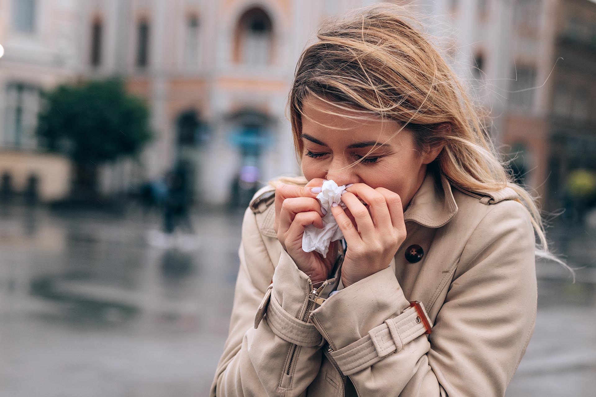 Woman sneezing into tissue