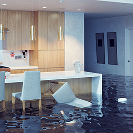 A flooded kitchen with water covering the floor, a tipped-over chair, and modern cabinetry in the background.