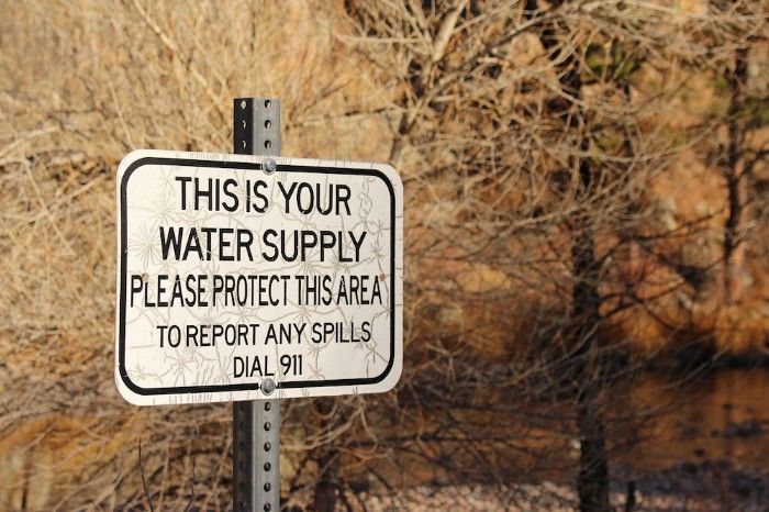 Sign warning to protect the water supply and report spills by dialing 911.