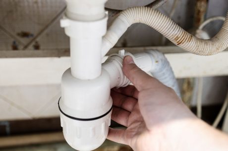 Plumber installing a plastic siphon in the kitchen