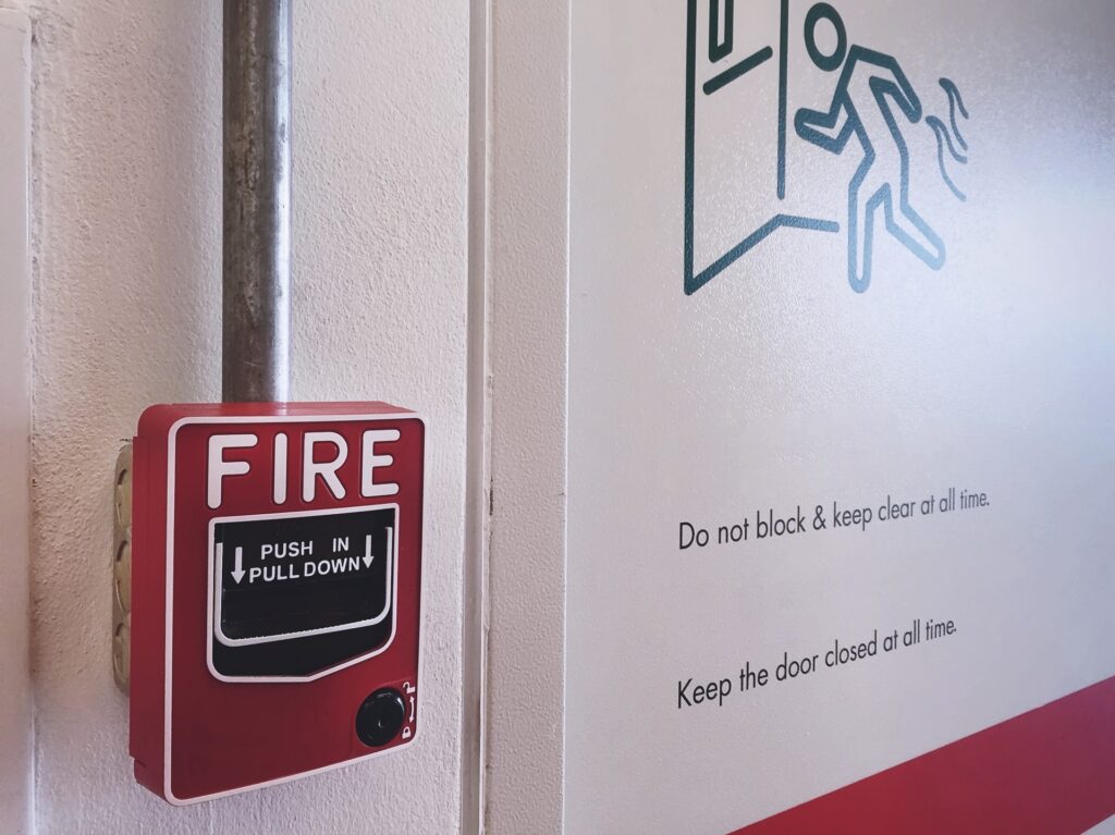 Close-up of red fire alarm box near an emergency exit