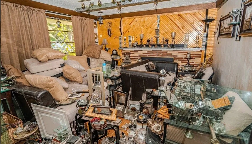 Cluttered living room filled with piles of furniture, pillows, and various items, illustrating the impact of hoarding.