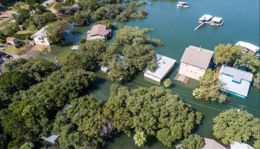 Aerial view of homes partially submerged in water, surrounded by trees, illustrating severe water damage.