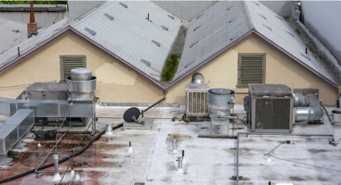 Flat rooftop with HVAC units and drainage, showing potential areas for water damage in office buildings.