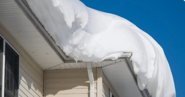 Snow accumulation on a roof, highlighting the need for snow removal for homeowners.
