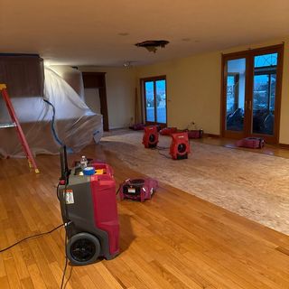 Drying equipment and covered furniture in a room undergoing water damage restoration.