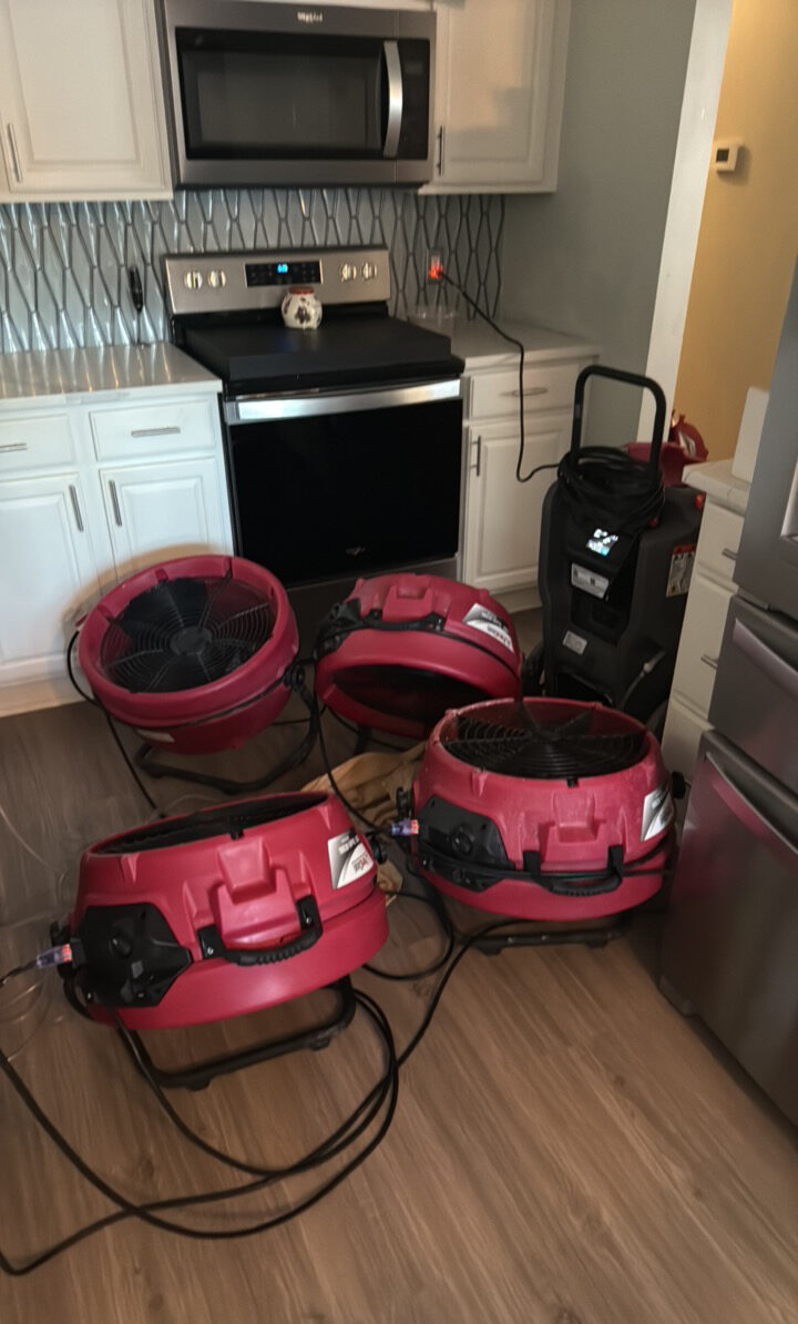 Air movers and dehumidifier drying a kitchen after water damage