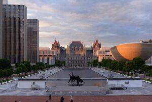 Empire State Plaza at sunset featuring the historic Capitol, modern buildings, and The Egg. TITLE