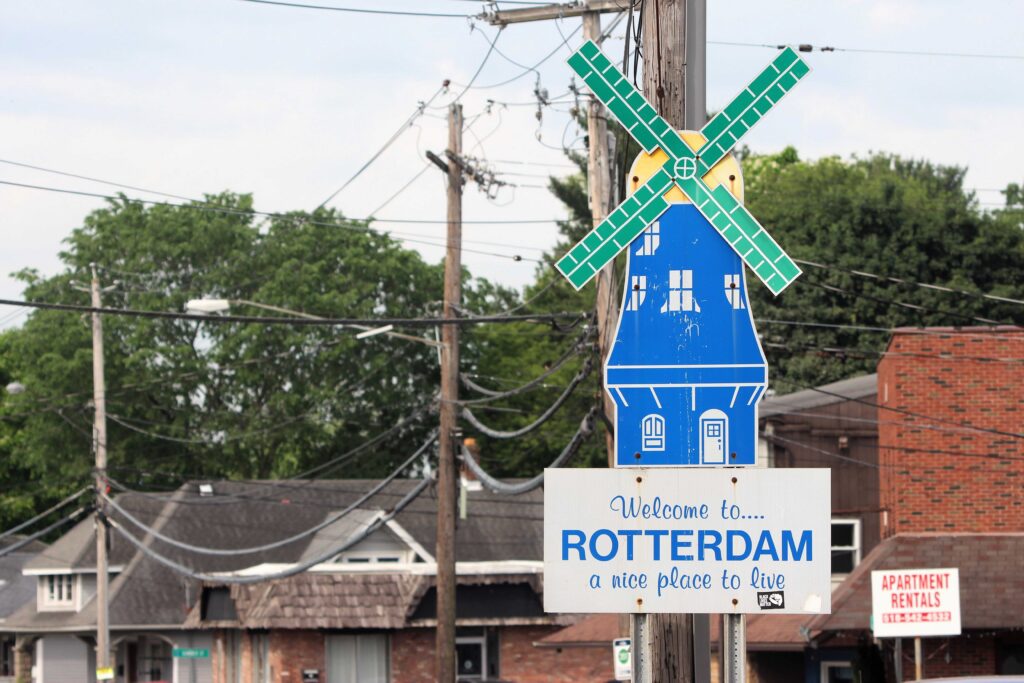 A blue windmill-shaped sign on a utility pole welcomes visitors to Rotterdam, a nice place
