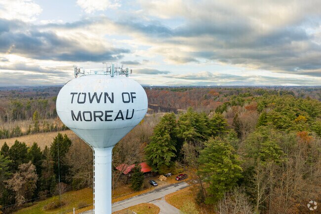 White Town of Moreau water tower overlooks a vast autumn forest under a dramatic cloudy sky.