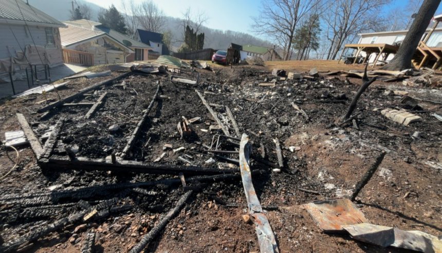 Residential fire mitigation is shown in a heavily destroyed garage structure with collapsed walls, exposed framing, and extensive fire-related debris scattered across the ground. The interior is charred and filled with burned materials, highlighting severe structural loss and smoke damage throughout the building.