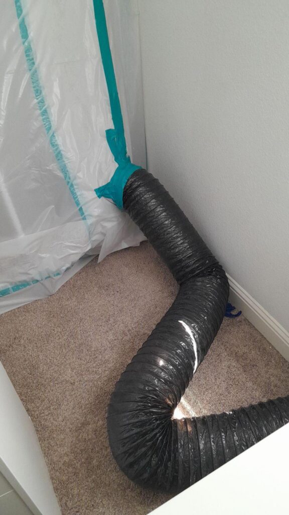 A HEPA vacuum hose leading into the contaminated area.