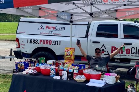 PuroClean booth set up with goodies and information. Man sitting at table to raise awareness.