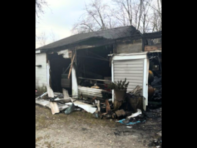 Residential fire mitigation is shown in a heavily destroyed garage structure with collapsed walls, exposed framing, and extensive fire-related debris scattered across the ground. The interior is charred and filled with burned materials, highlighting severe structural loss and smoke damage throughout the building.