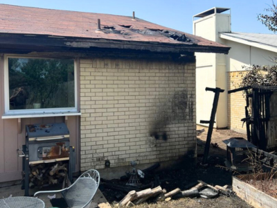 Structural fire damage to a Dallas-area home with visible scorch marks, roof damage, and burned exterior materials.