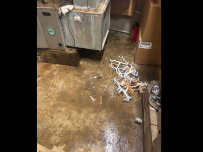 Standing water and puddle accumulation on a concrete basement floor next to a leaking HVAC unit, highlighting the need for professional water damage restoration