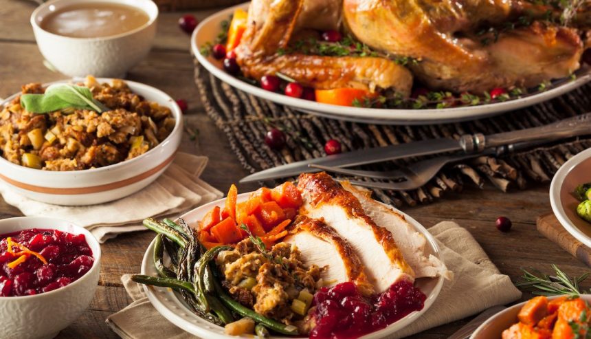 Thanksgiving dinner spread featuring turkey, stuffing, cranberry sauce, and vegetables on a rustic table.