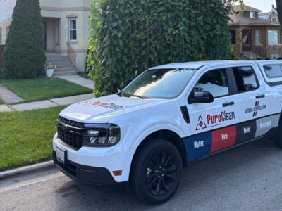 PuroClean service vehicle parked in front of a residential property undergoing code-compliant reconstruction, ready for emergency restoration deployment.