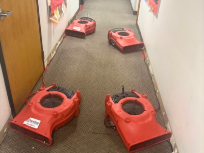 "Commercial water damage restoration in progress. Several air movers are placed along a hallway to aid in the drying process, following water damage. The equipment helps ensure effective moisture removal in commercial properties.