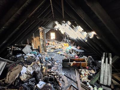 Severe attic destruction after a house fire showing smoke and debris before smoke damage restoration.