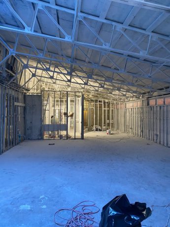 New commercial building interior under construction with metal stud framing and exposed ceiling trusses. TITLE: