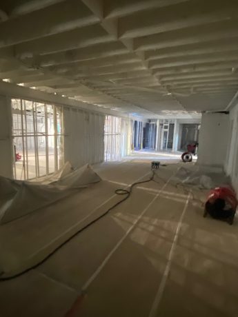 Spacious room under renovation with white spray foam insulation covering the ceiling and walls. TITLE