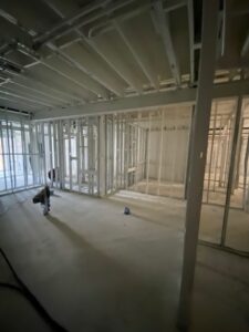 A new building interior framed with metal studs and a freshly poured concrete floor during construction.