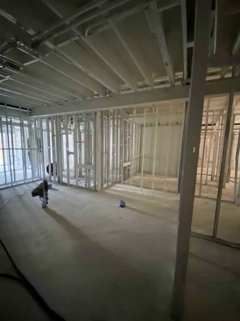 A new building interior framed with metal studs and a freshly poured concrete floor during construction.