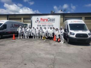 A large PuroClean team in white protective suits stands in front of their branded service
