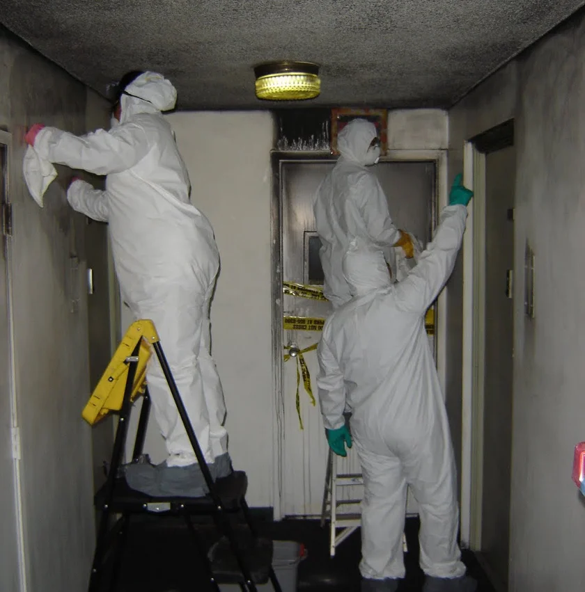 fire damage restoration technicians cleaning soot from walls residential home