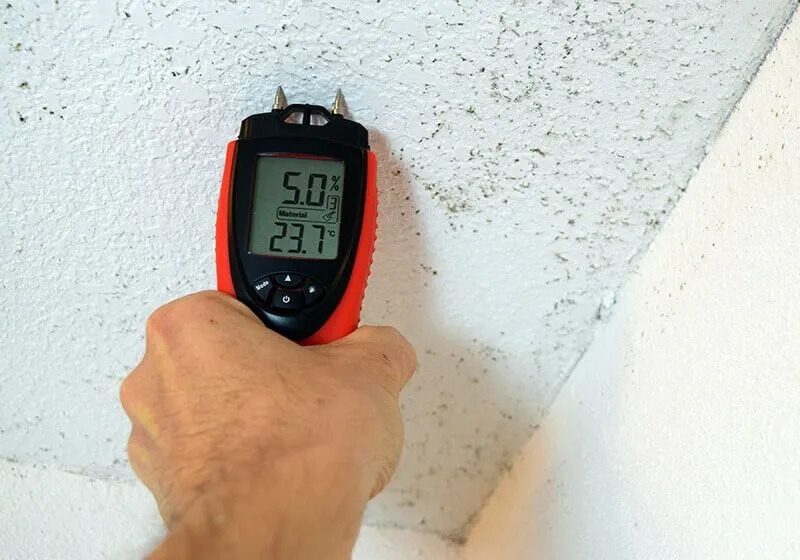 Technician inspecting a wall cavity with a moisture meter in an Ormond Beach home