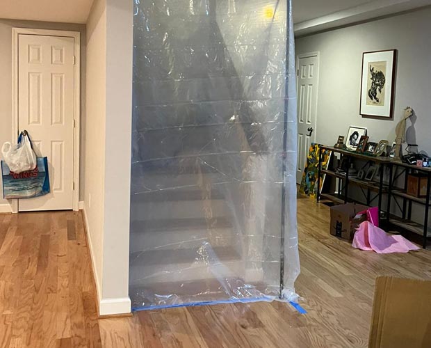 Mold remediation technicians setting up containment barriers and HEPA filtration units